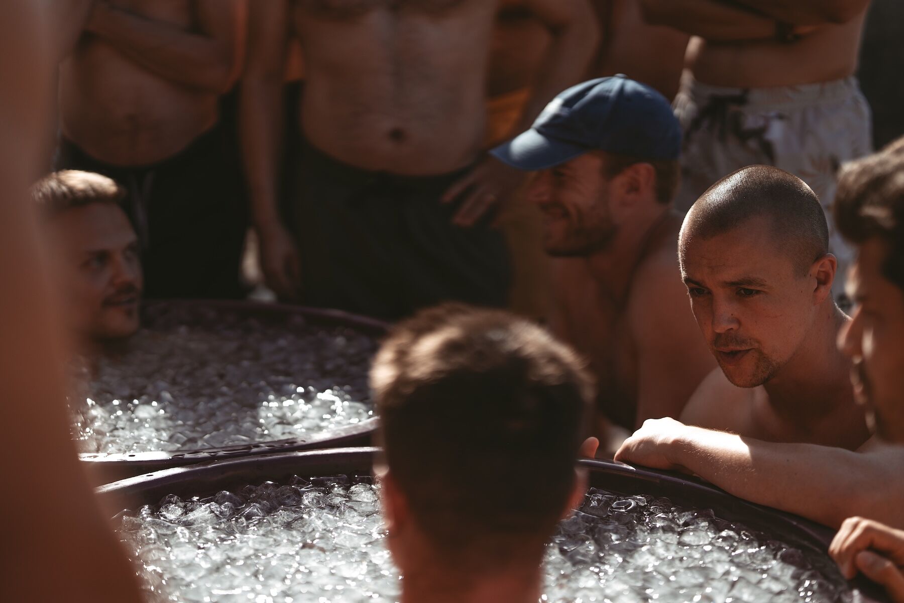Men submerged in ice baths as the others gather round at The Return of Men retreat, October 2025.