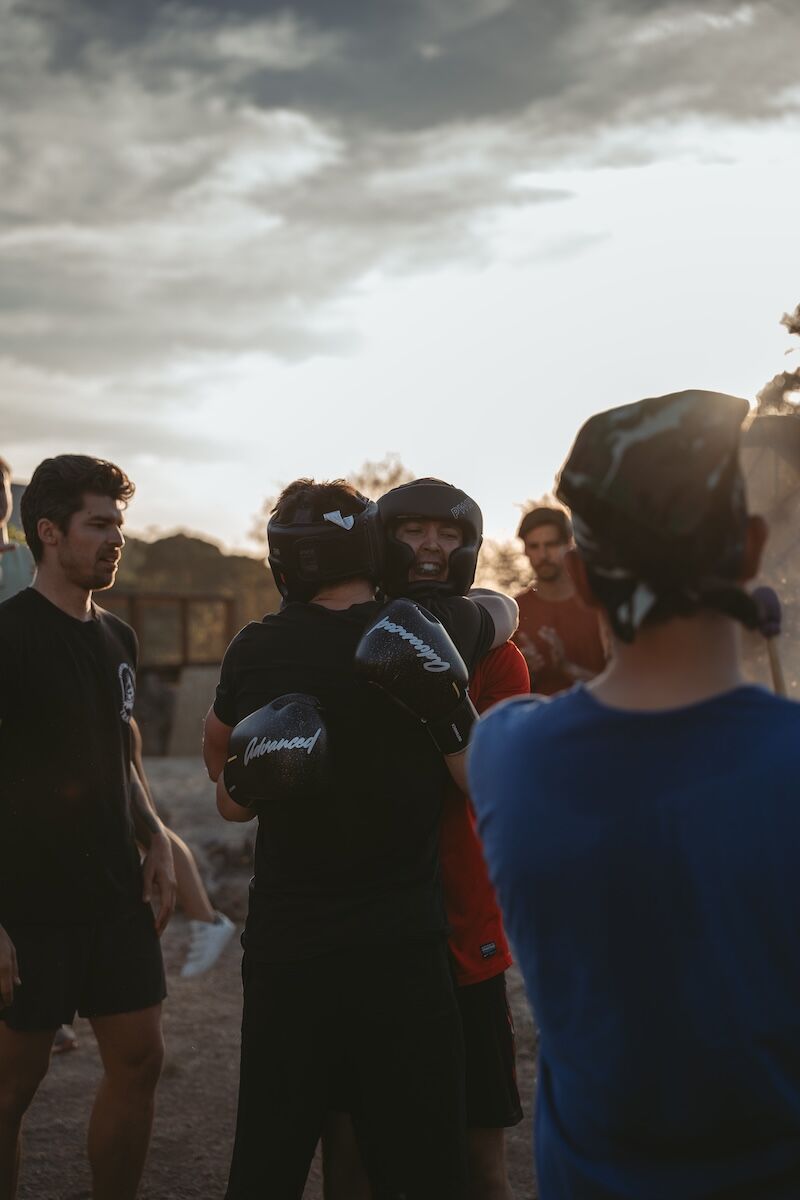 Two men in headguards and gloves embrace after sparring at The Return of Men retreat, Portugal, October 2025.