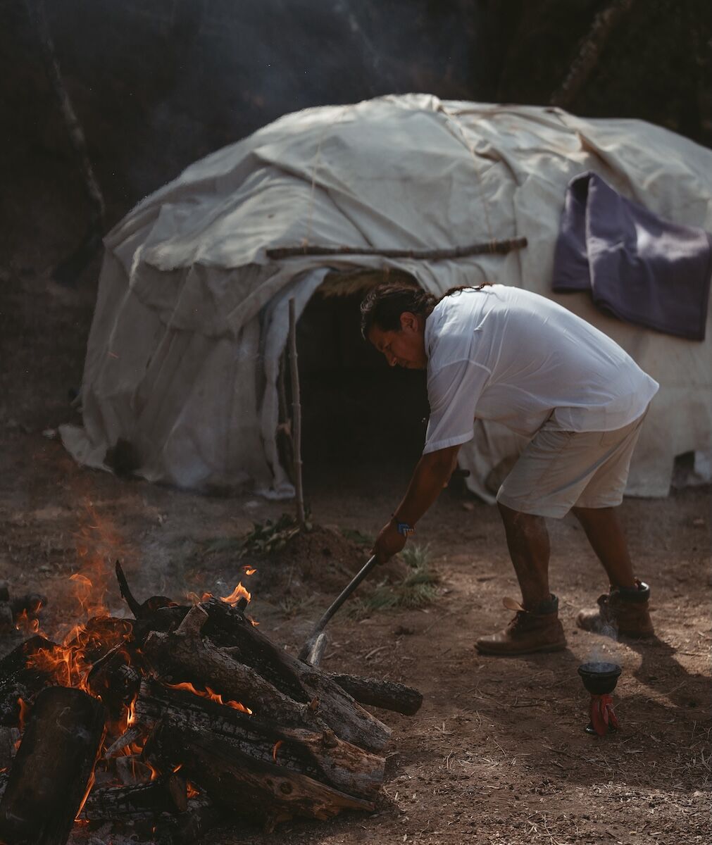 Santiago tending to the fire before the Temazcal ceremony, symbolising sacred preparation, purification, and ancestral wisdom.