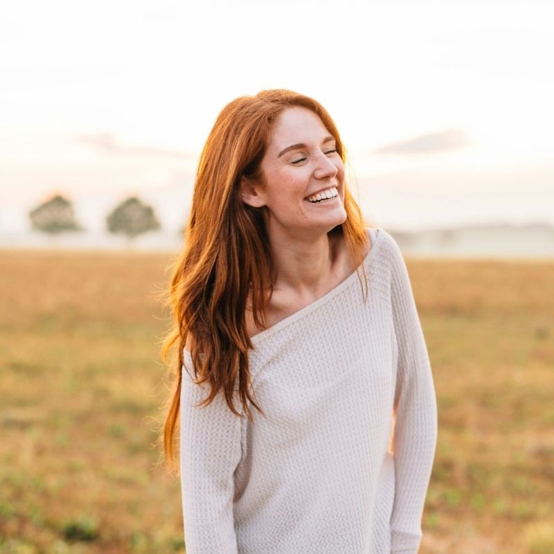 Leyla Grant, entrepreneur, smiling in a golden field — reflecting clarity, focus, and balance gained through Martin Thomsen’s transformative microdosing coaching.