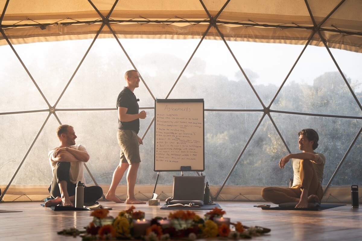 A guide teaches at a flipchart in the geodesic dome at first light at The Return of Men retreat, BioVilla, May 2026.