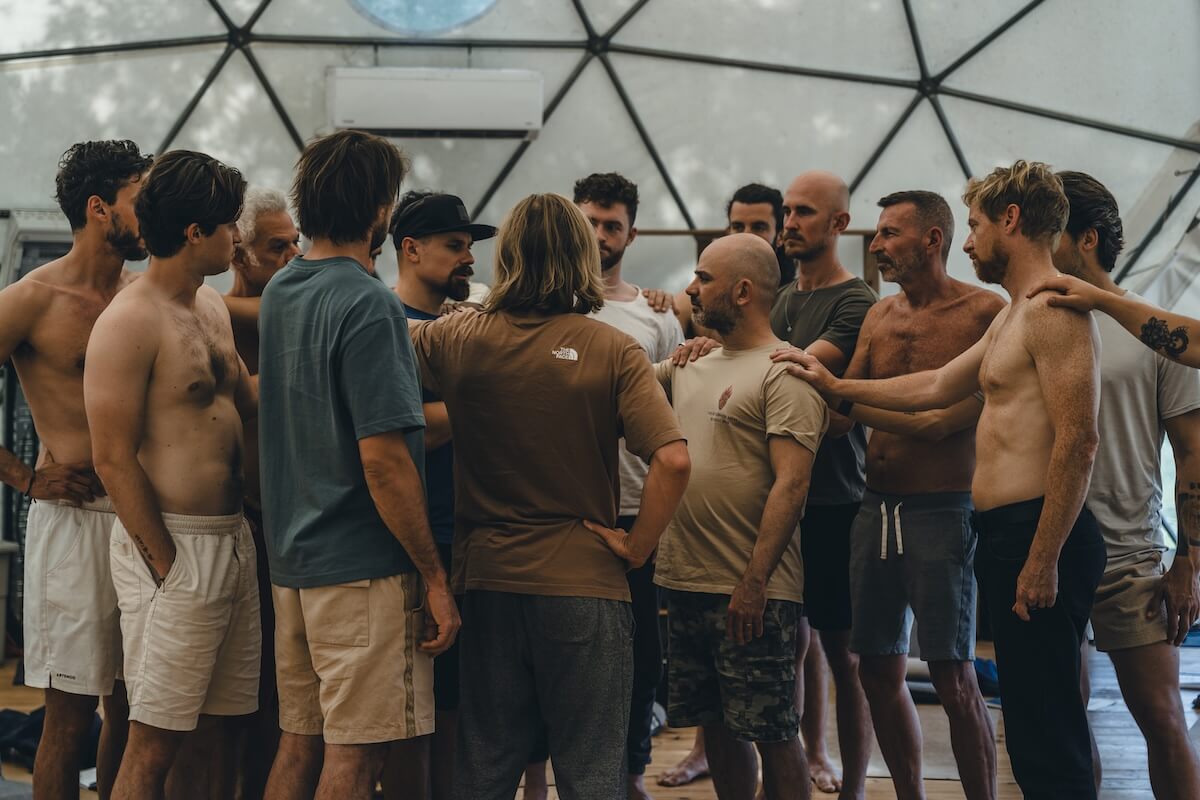 The men gather close in the geodesic dome, two facing each other at the centre, at The Return of Men retreat, May 2026.