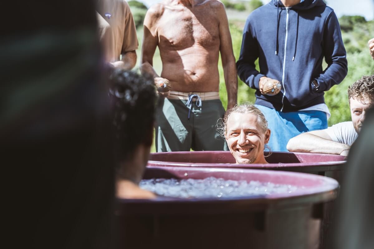 A man laughs from the ice bath as the circle grins around him at The Return of Men retreat, BioVilla, 2026.