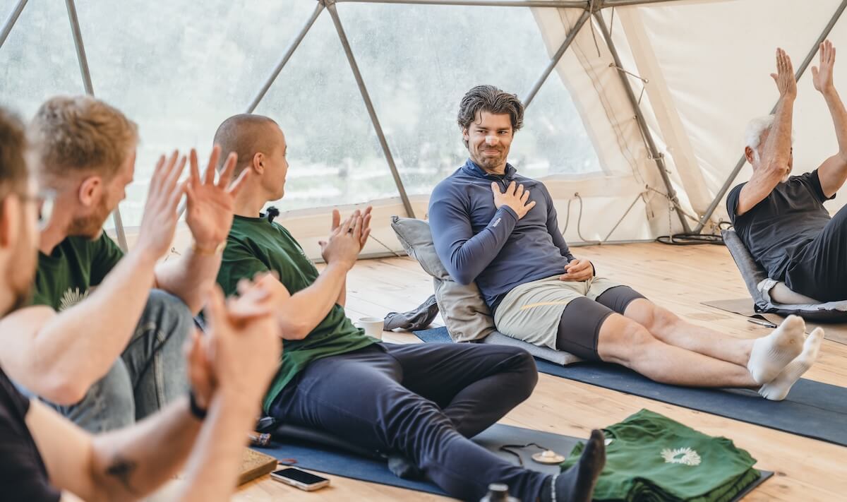 A man rests a hand on his heart as the circle applauds him at The Return of Men retreat, BioVilla, May 2026.
