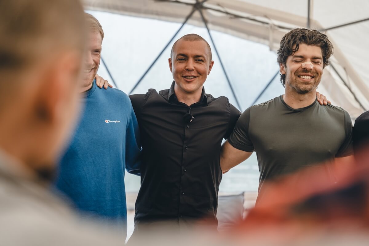 Martin Thomsen stands arm in arm with the men in the dome circle at The Return of Men retreat, BioVilla, 2026.