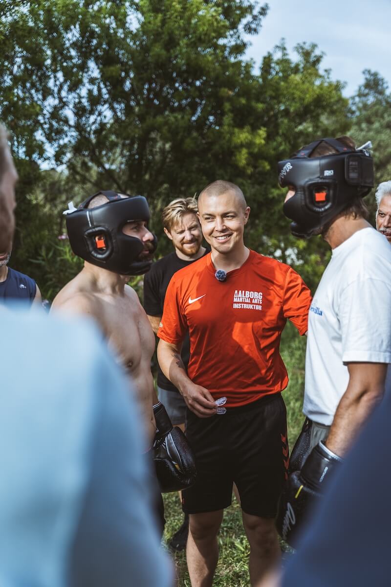 Martin Thomsen smiles among men in headguards before the sparring rounds at The Return of Men retreat, 2026.