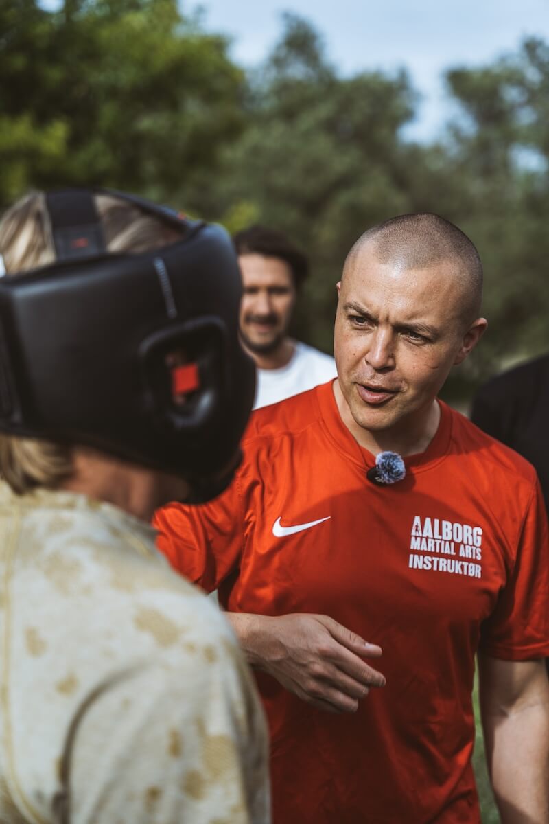 Martin Thomsen coaches a man in a headguard between rounds at The Return of Men retreat, Portugal, May 2026.