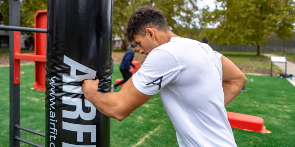 man in white t-shirt and white shorts holding black and white metal pole