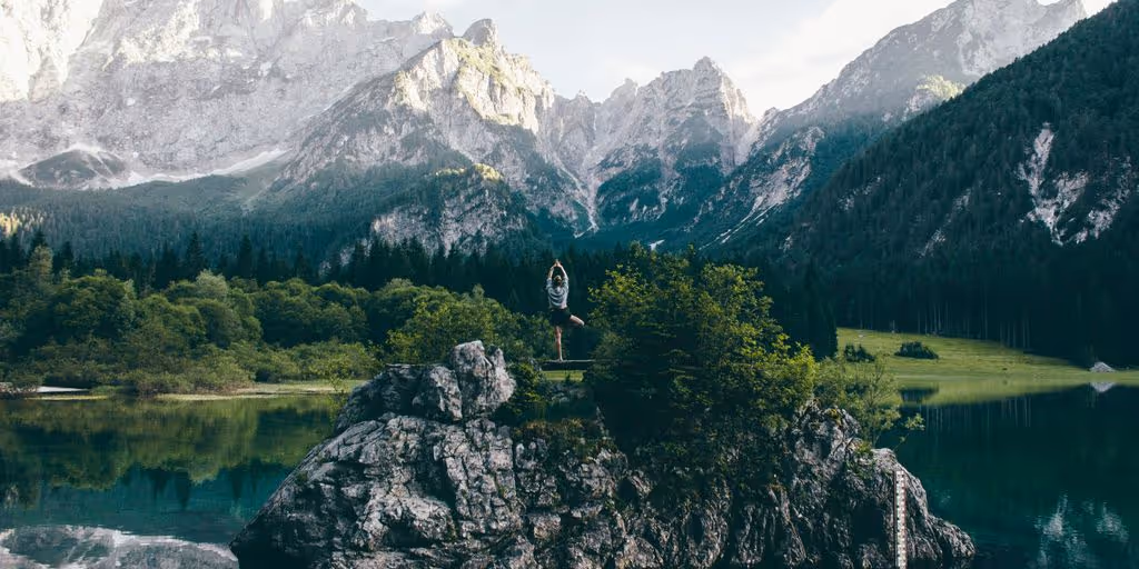 person standing on rock formation surrounded by body of water