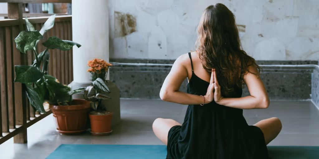 woman wearing black shirt sitting on green yoga mat