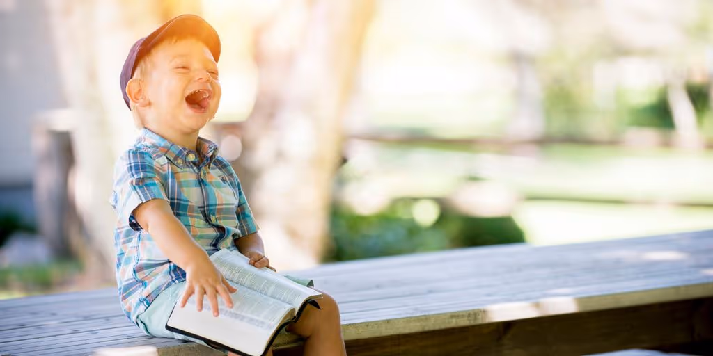 boy sitting on bench while holding a book