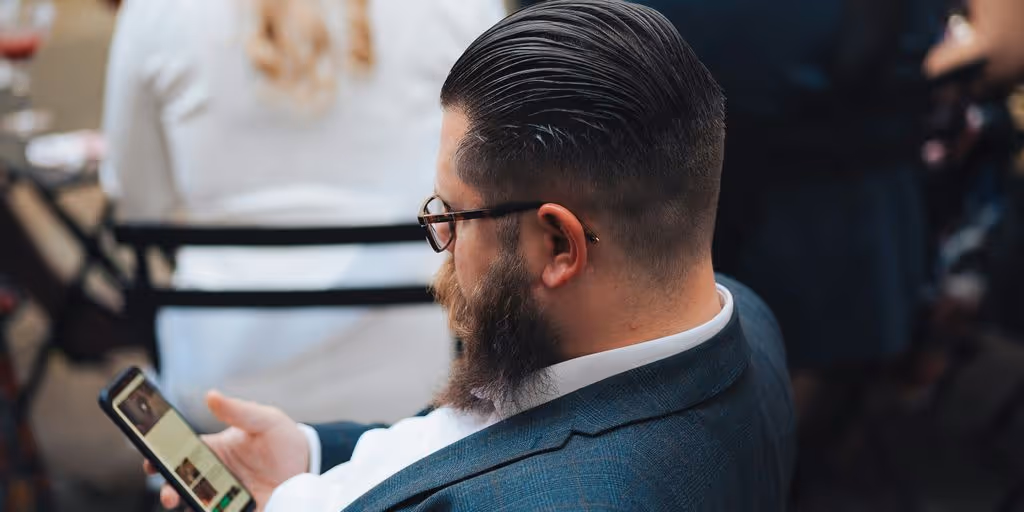 a man sitting in a chair looking at his cell phone