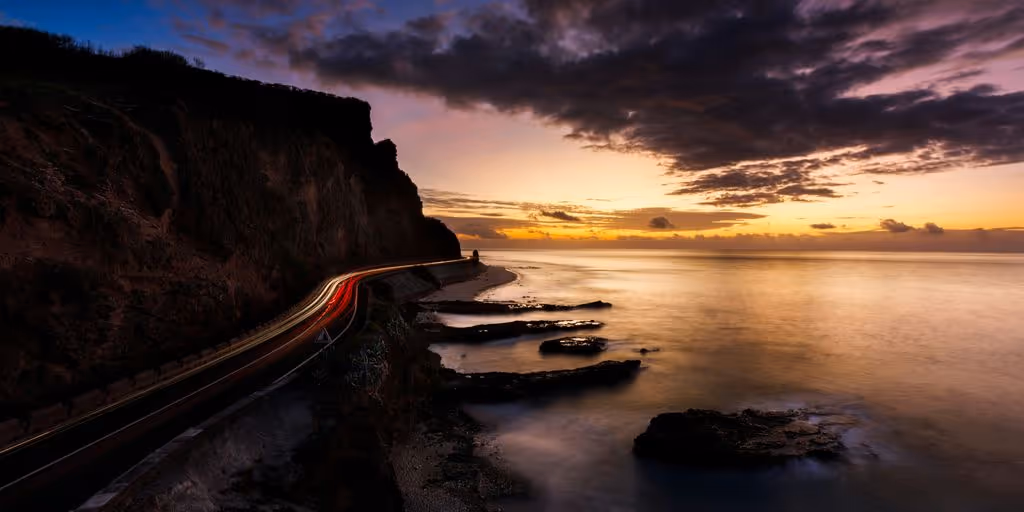 body of water near mountain during sunset