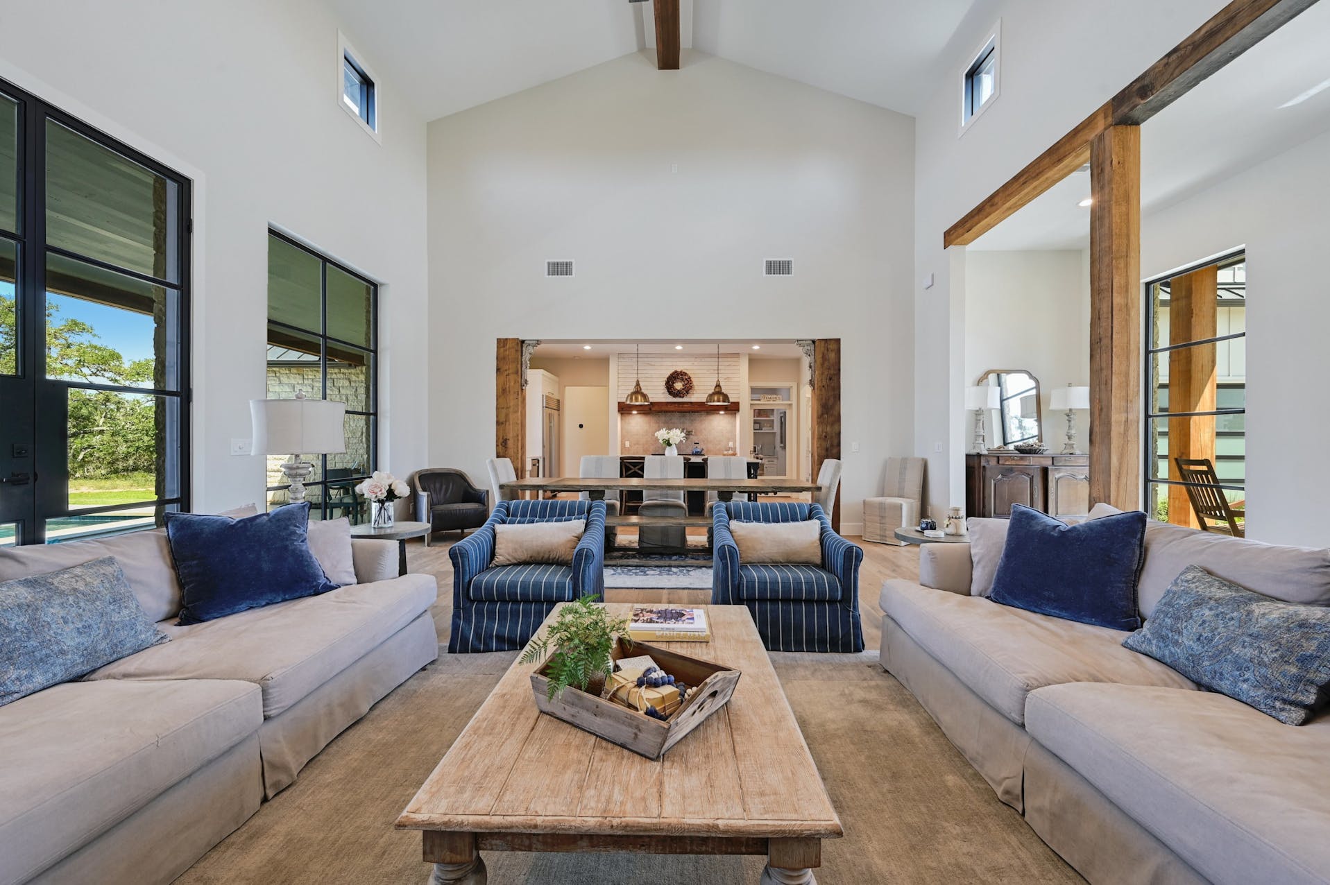 Living room with blue and cream sofas under a beamed ceiling and large windows