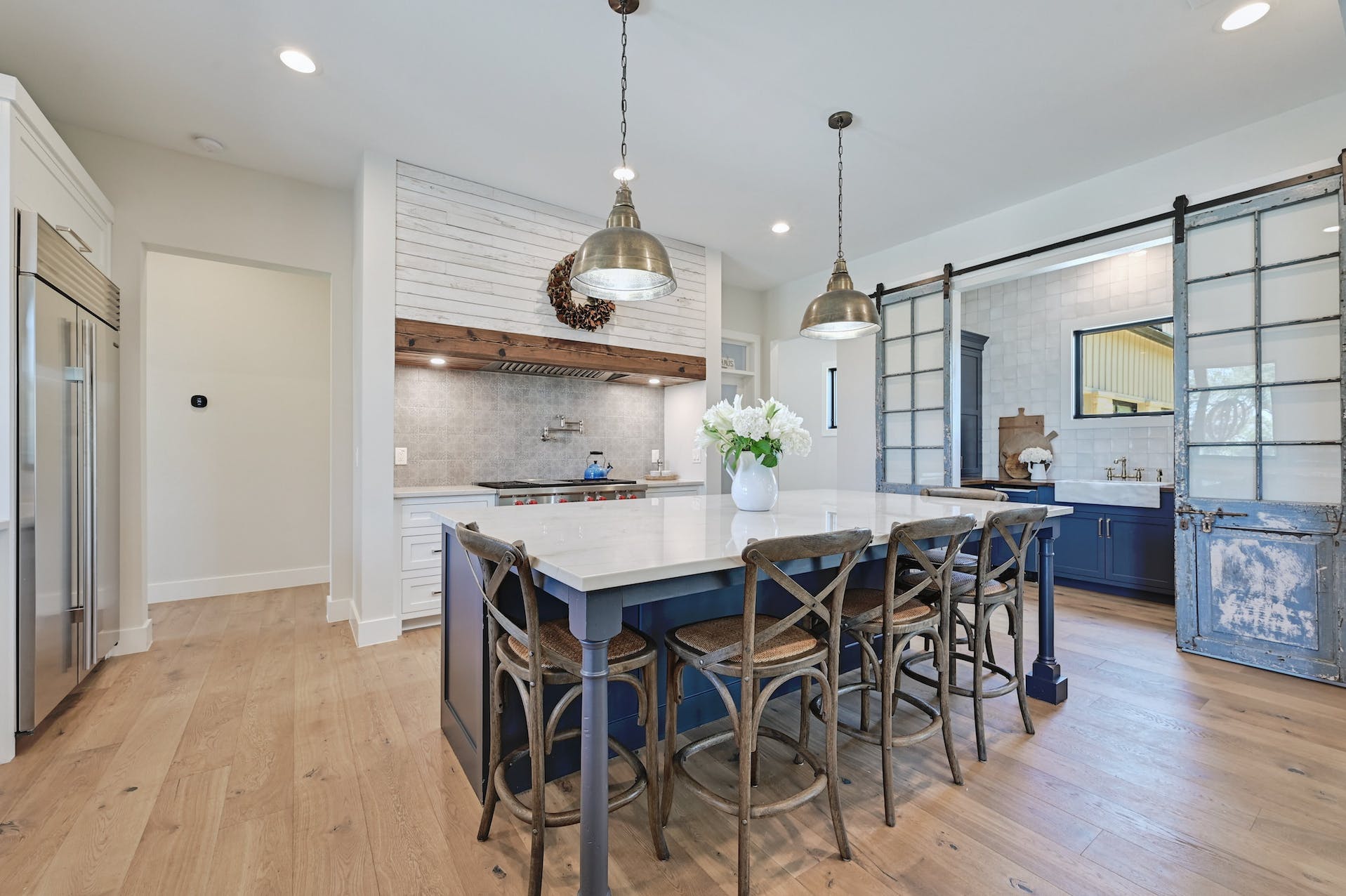 Kitchen with a navy island, pendant lights and sliding barn doors