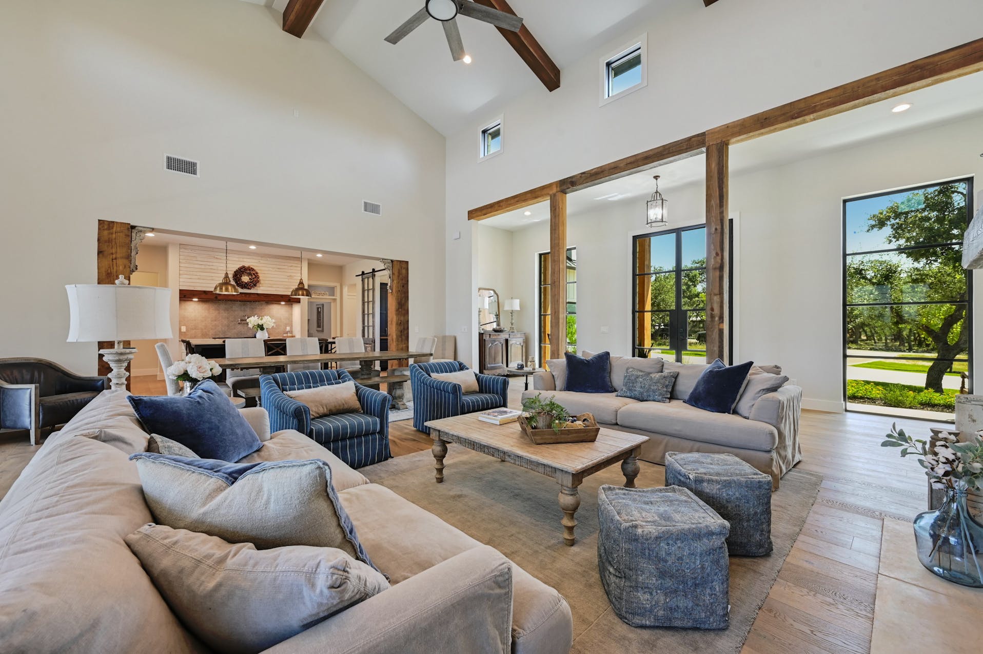 Open living and dining area with wood beams and windows to the yard