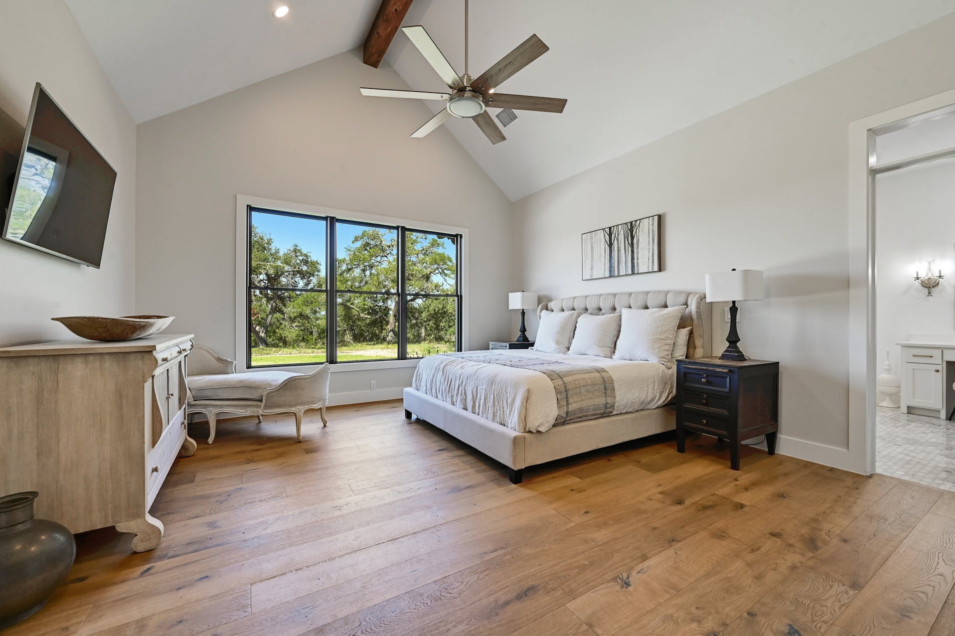 Bedroom with a vaulted ceiling, ceiling fan and large windows