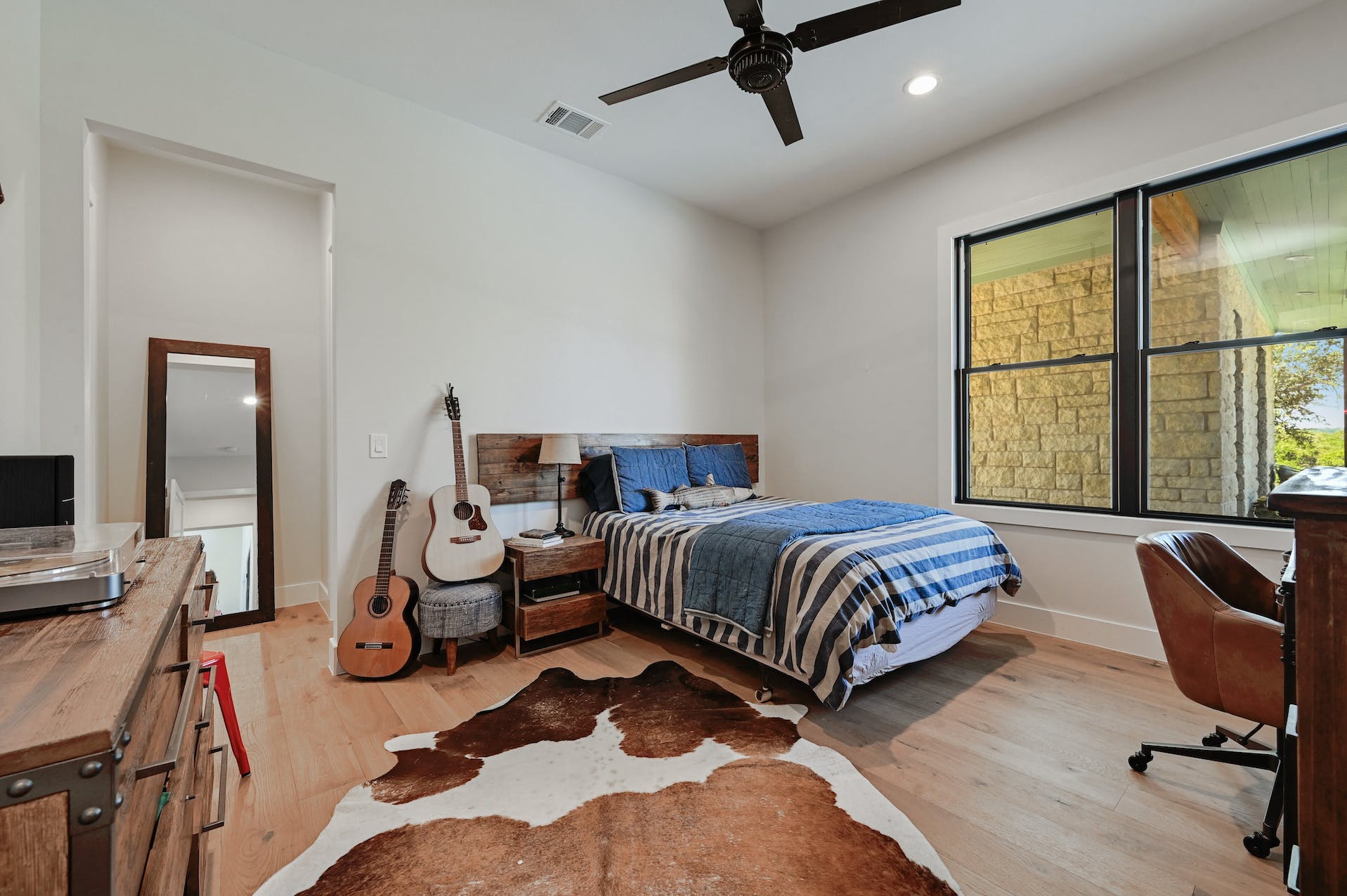 Bedroom with plaid bedding, a cowhide rug and large windows