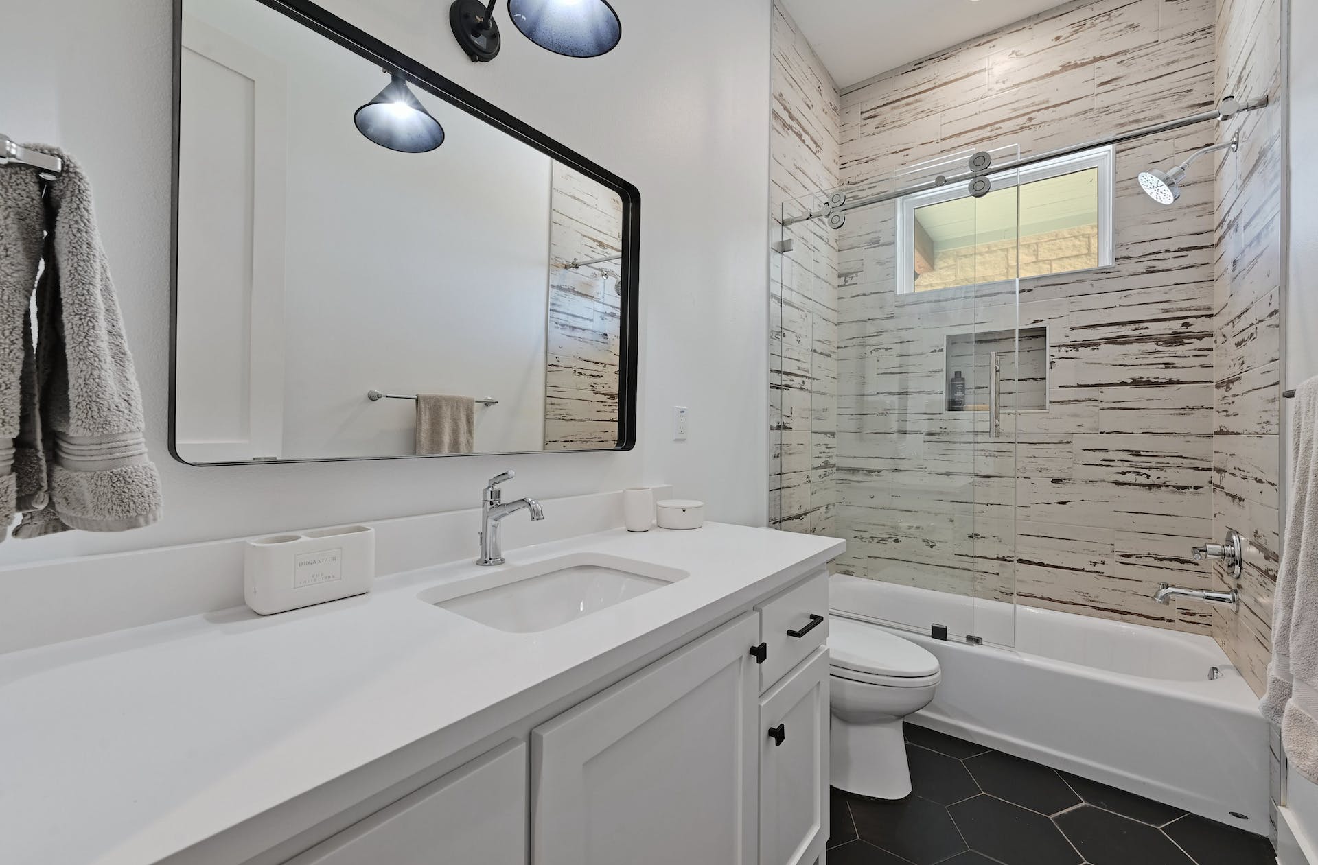 Bathroom with a white vanity, large mirror and tiled tub-shower