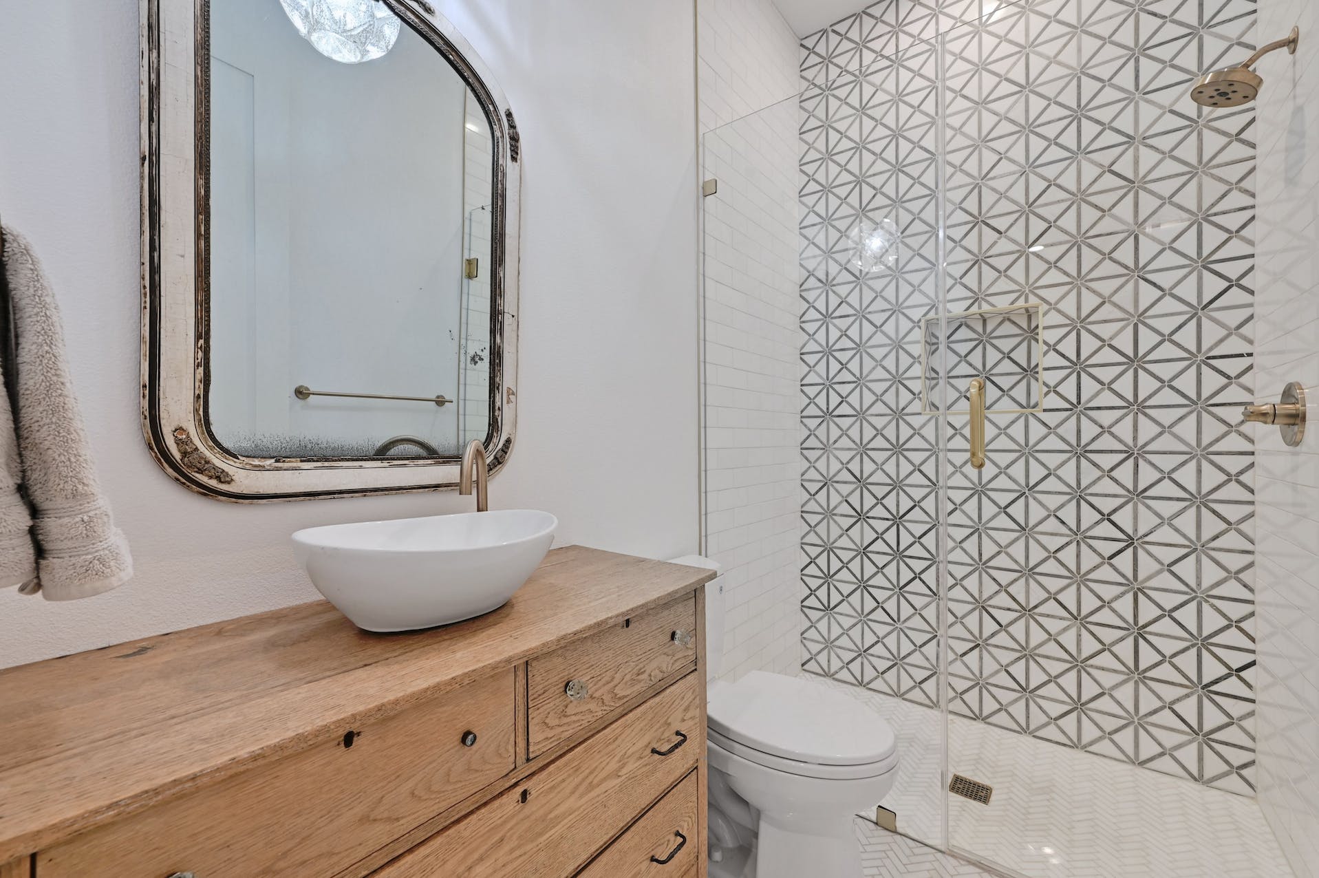 Bathroom with a wood vanity, vessel sink and patterned tile shower