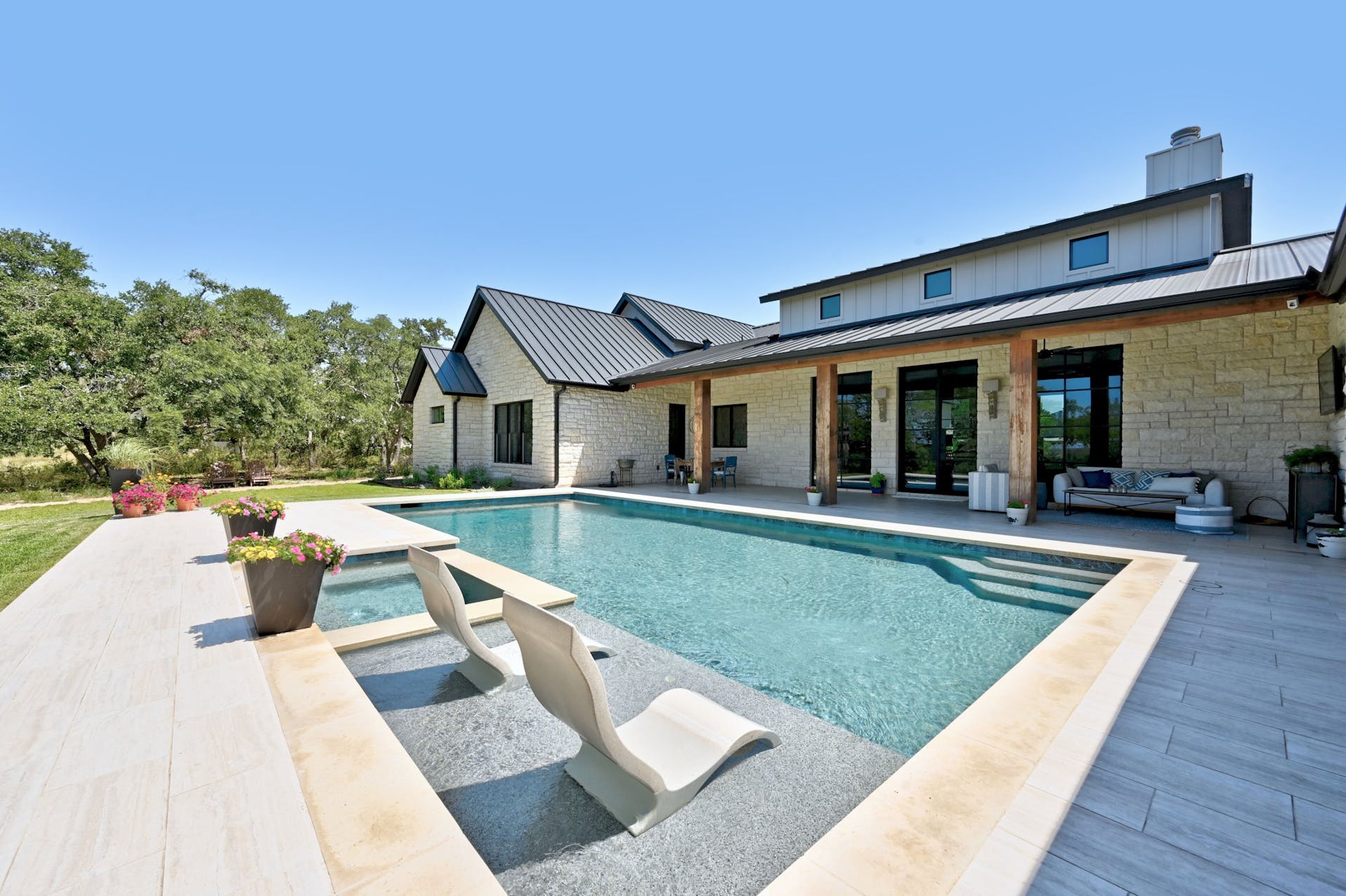 Pool with a sun shelf and loungers behind the home