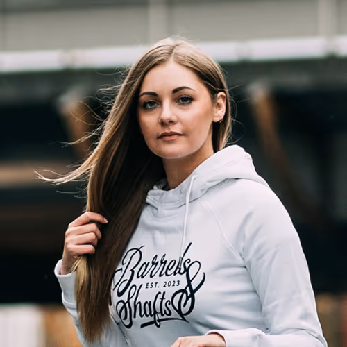 young woman wearing barrels & shafts hoodie infront of a bridge