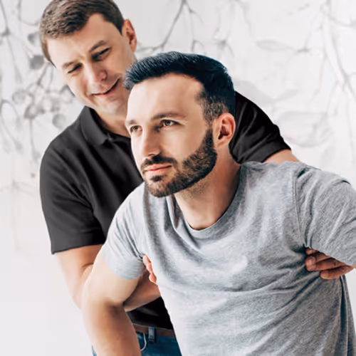 Physiotherapeut hilft einem Mann aus seinem Rollstuhl, um die Physiotherapiestunde zu beginnen