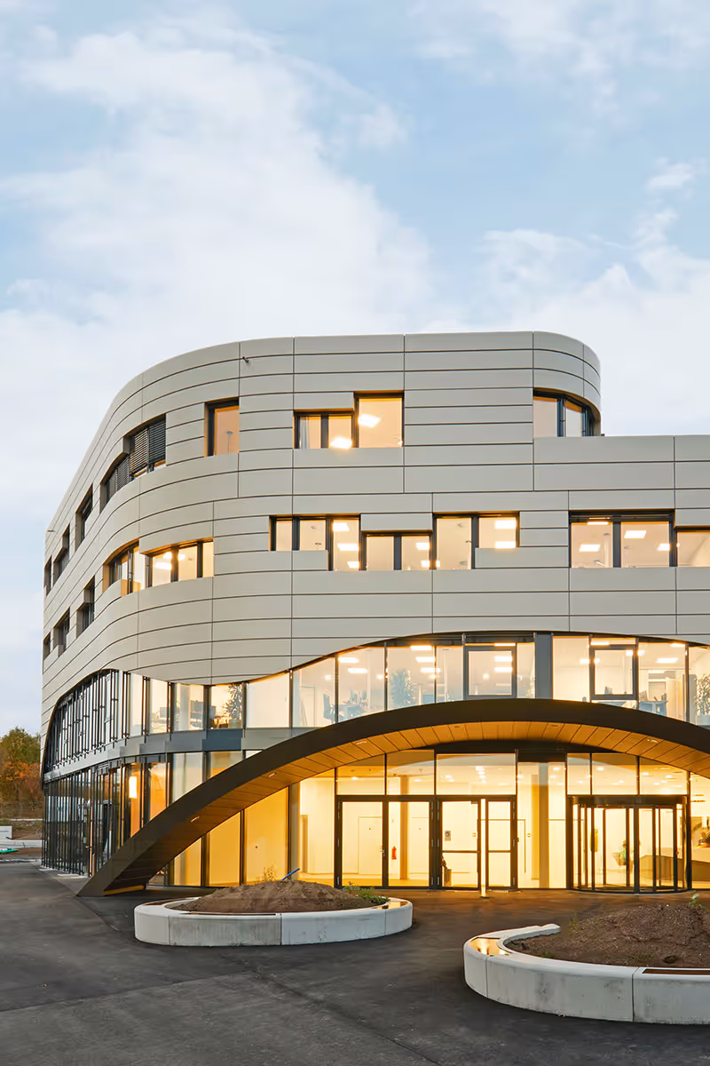 Bild eines Gebäudes mit außergewöhnlicher Fassade, das innen mit warm-weißem Licht versehen ist. Wirkt Warm und gemütlich