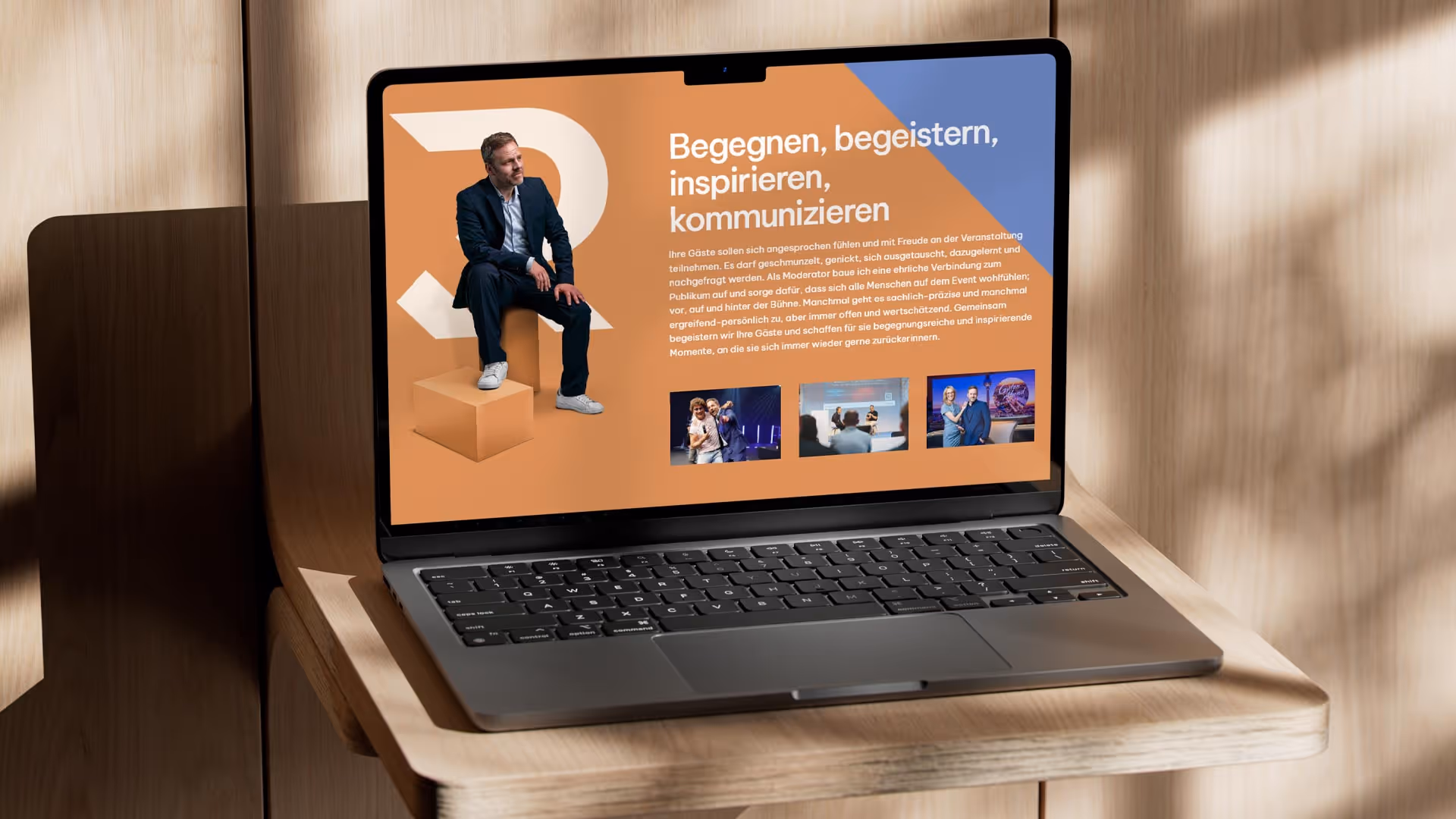 Aufgeklappter Laptop auf einem Holzständer vor einer Holzwand. Robert Bittigs Website ist geöffnet.