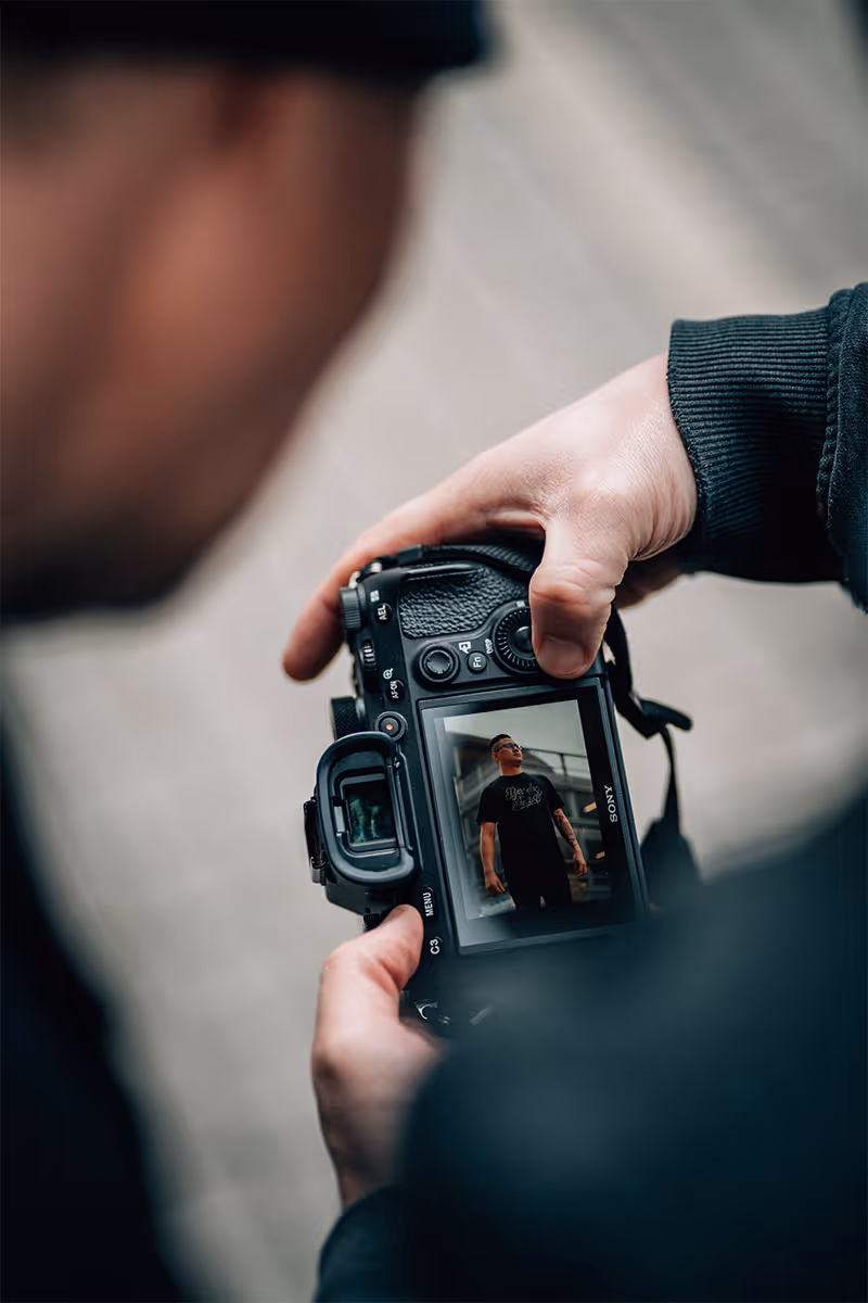 Kamera mit geschossenem Bild im Fokus. Im Vordergrund zwei Menschen begutachten das Bild.
