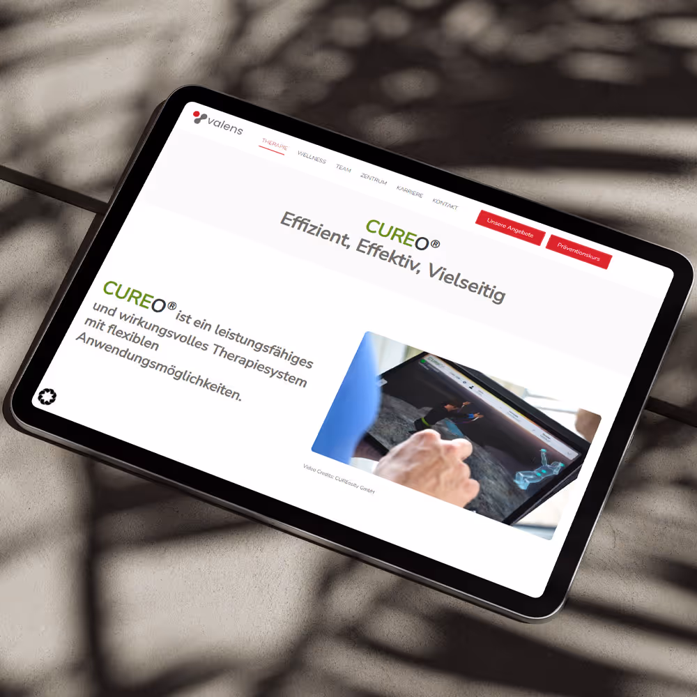 Tablet liegt im Schatten eines Baumes draußen auf Beton und zeigt einen Website Entwurf.