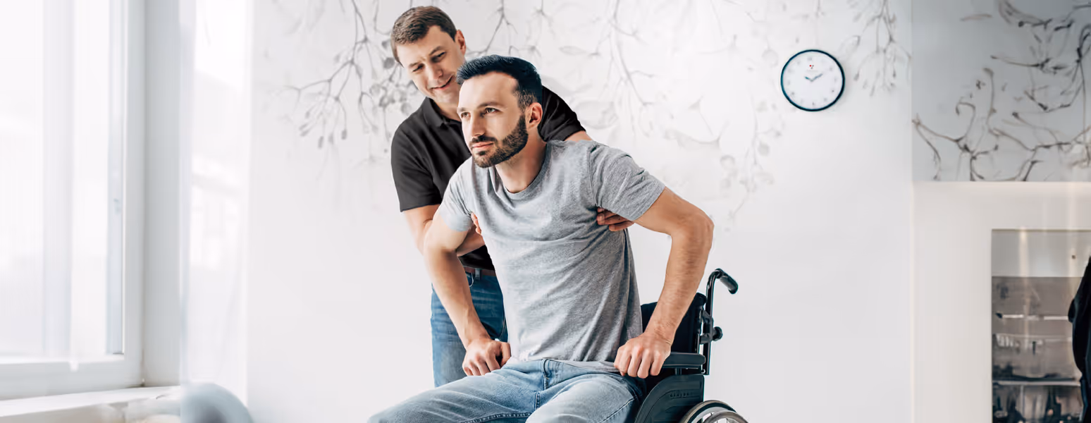 Physiotherapeut hilft einem Mann aus seinem Rollstuhl, um die Physiotherapiestunde zu beginnen
