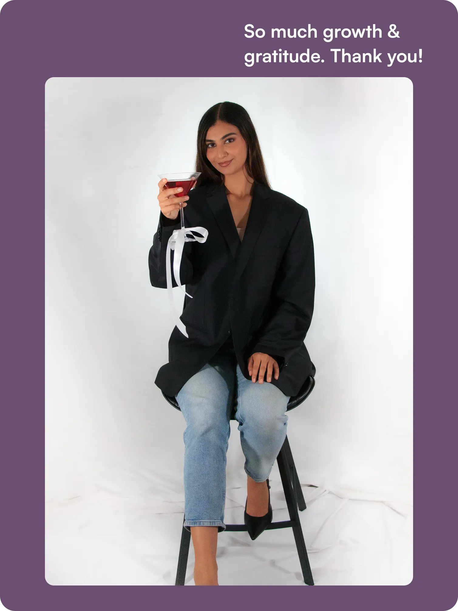 SipTales founder seated with a red mocktail, celebrating the business's growth.