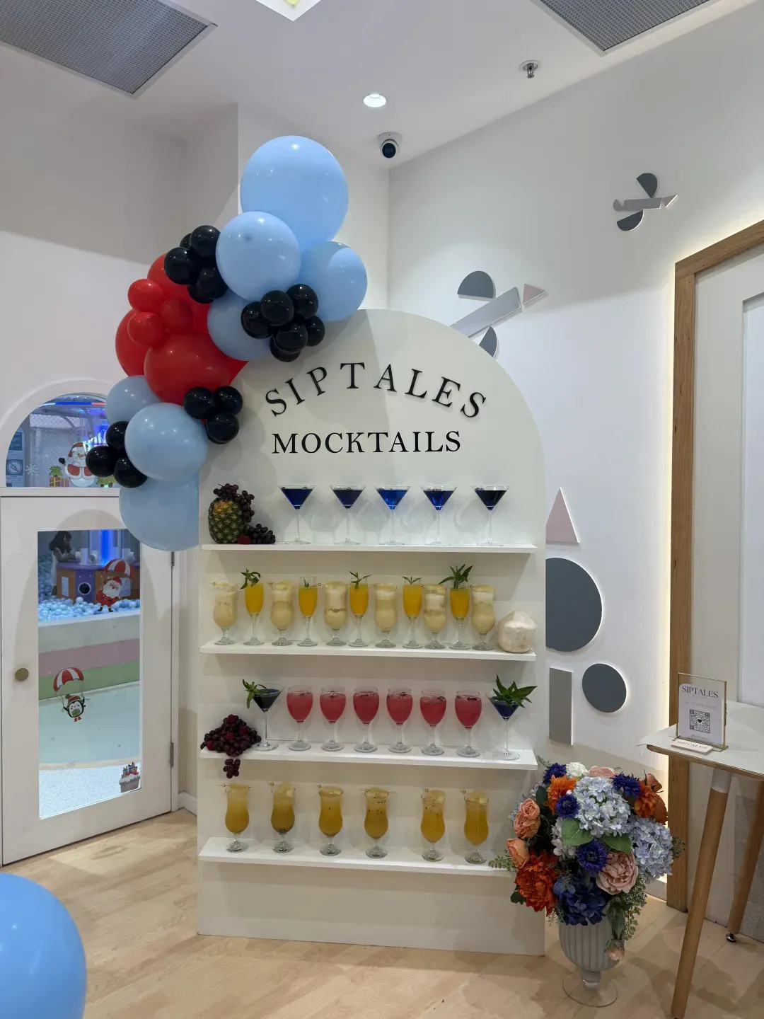 Branded SipTales mocktail wall styled with balloons