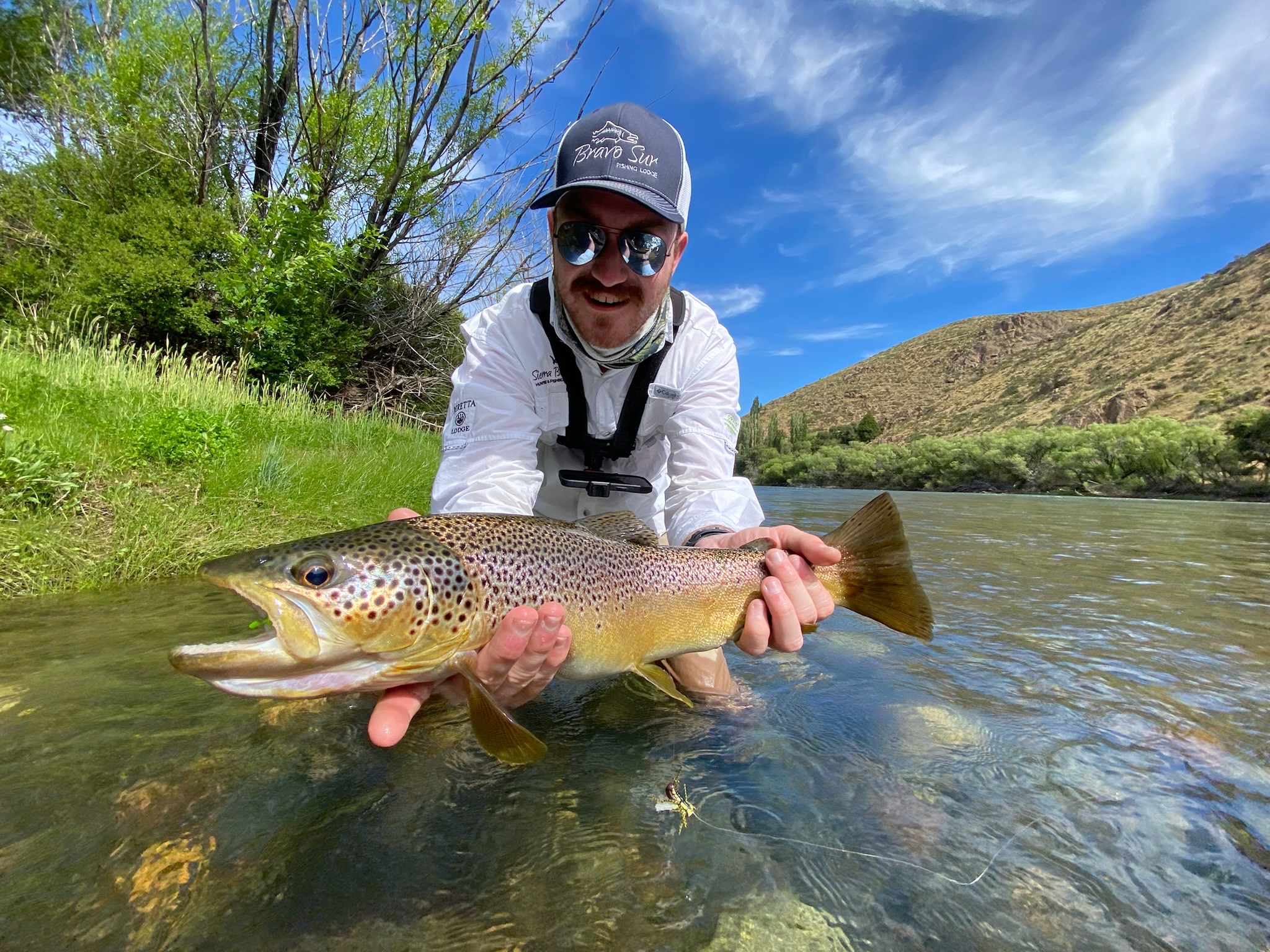 Angler kneeling with a trout catch in the river at Bravo Sur Lodge
