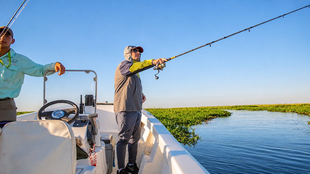Angler casting a spinning rod from the bow of a fishing boat