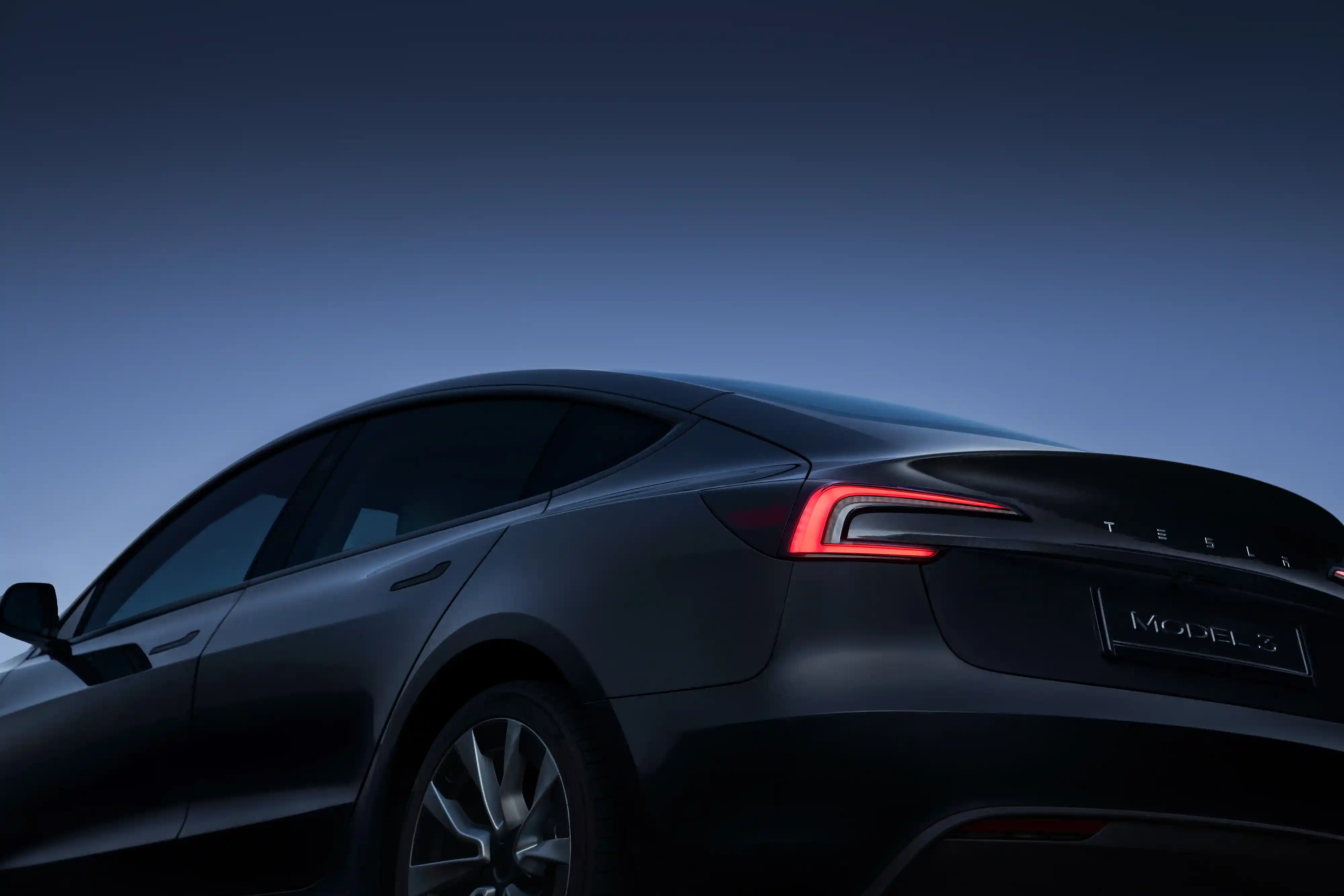 Rear view of Tesla Model 3 at dusk
