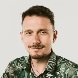 Portrait of Mateusz, a Delivery Leader with short hair and a beard, wearing a green, leaf-patterned shirt.