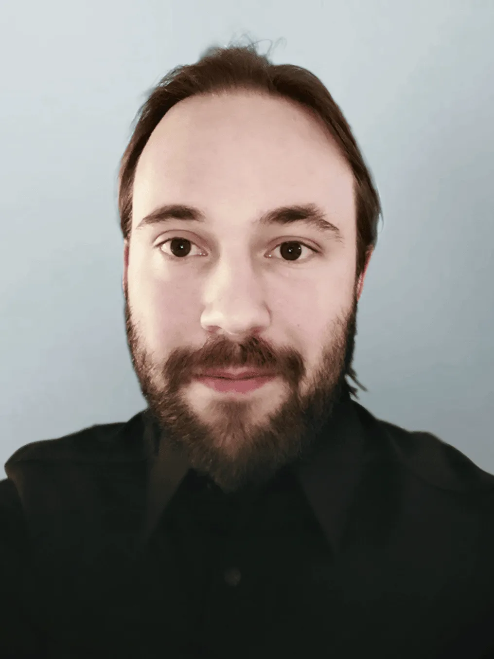 This is an image of Kevin Jahns, the creator of Yjs, wearing a black shirt and standing against a light gray background.