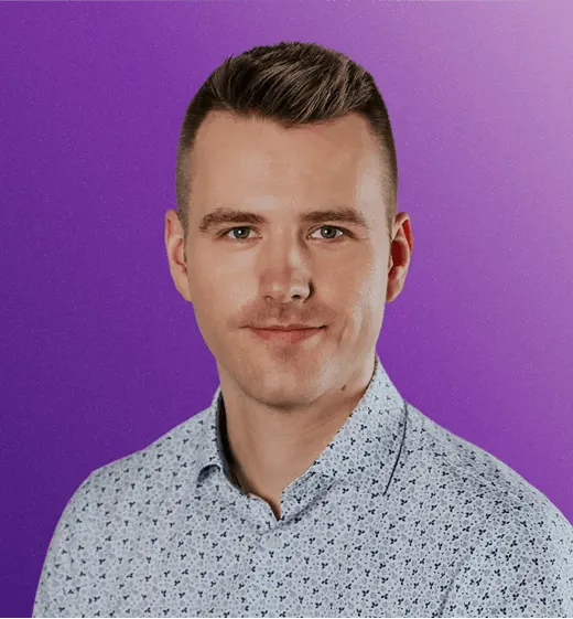 Professional portrait of a man in a patterned shirt against a purple gradient background, looking directly at the camera with a neutral expression.