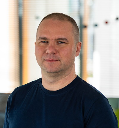 Portrait of a smiling bald man wearing a dark blue shirt in a bright indoor setting.