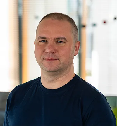 Portrait of a smiling bald man wearing a dark blue shirt in a bright indoor setting.
