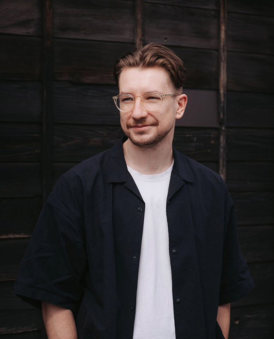 Headshot of Adam King, Product Designer, a white man with dark blonde hair, wearing glasses looking to the left of the camera.
