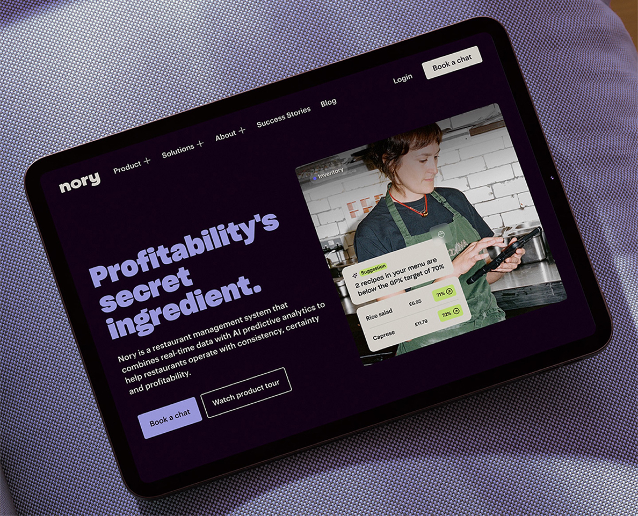 Nory's website homepage on an iPad, sitting on a purple sofa.