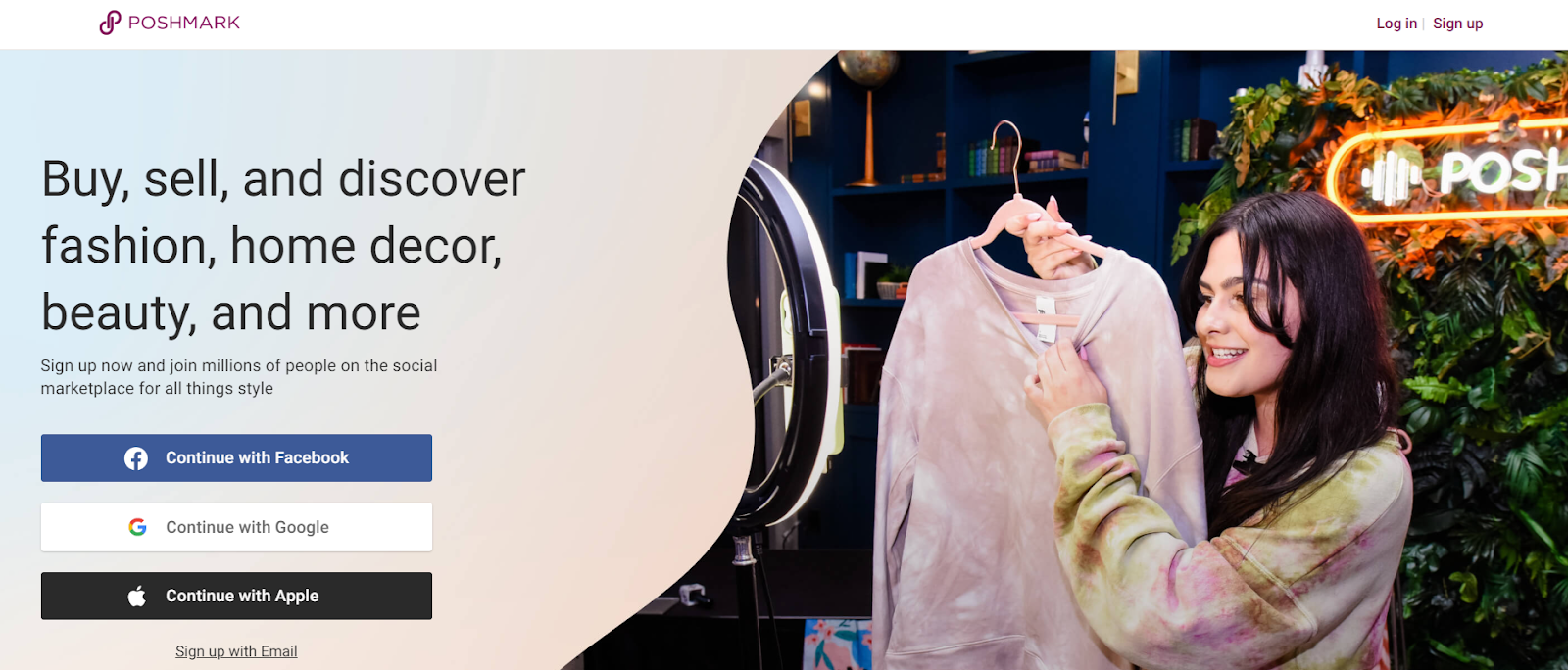 A screenshot of Poshmark’s landing page, with a prompt to sign up using Facebook, Google, or Apple. To the right is an image of a dark-haired woman holding a long-sleeved shirt on a clothes hanger, and to the left is the phrase “Buy, sell, and discover fashion, home decor, beauty, and more.”