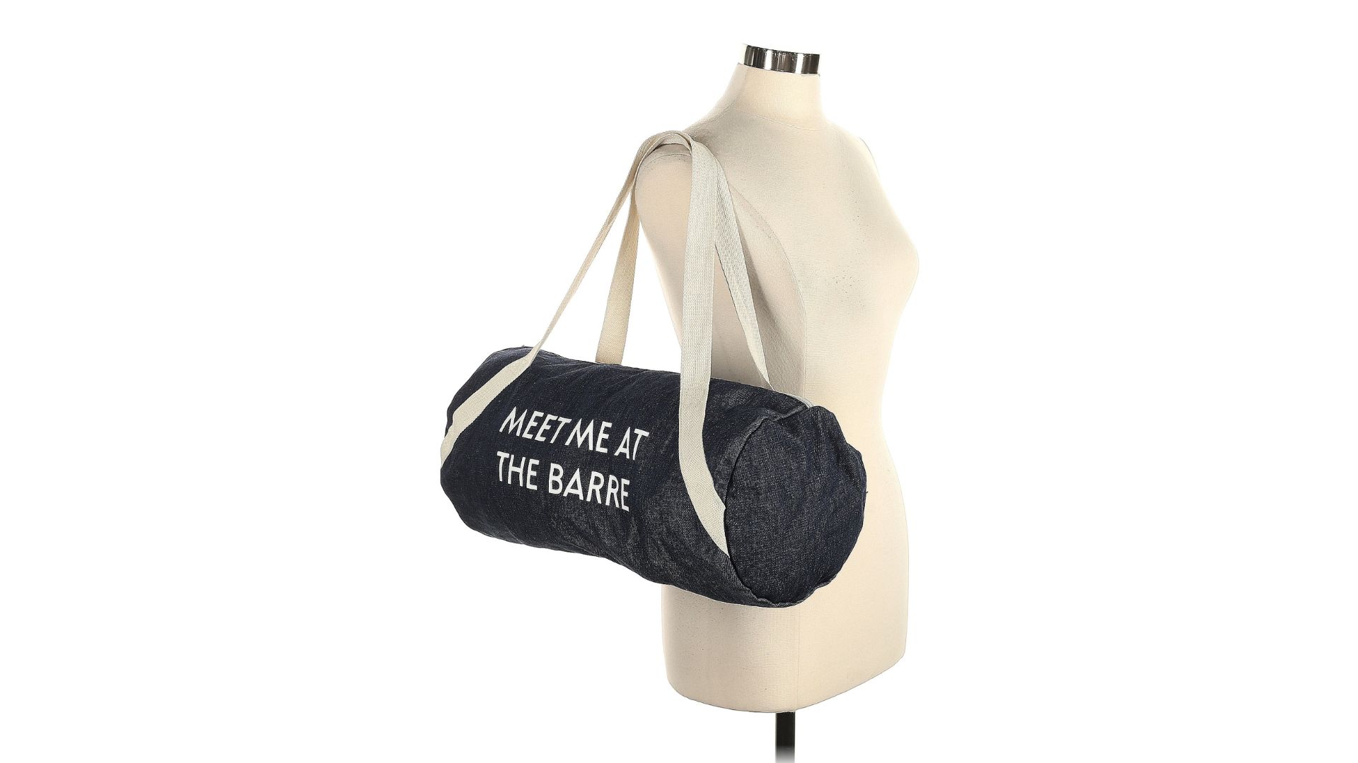 A dark gray barrel bag hanging from the straps on a torso-only mannequin and featuring the text 'Meet me at the barrel.'