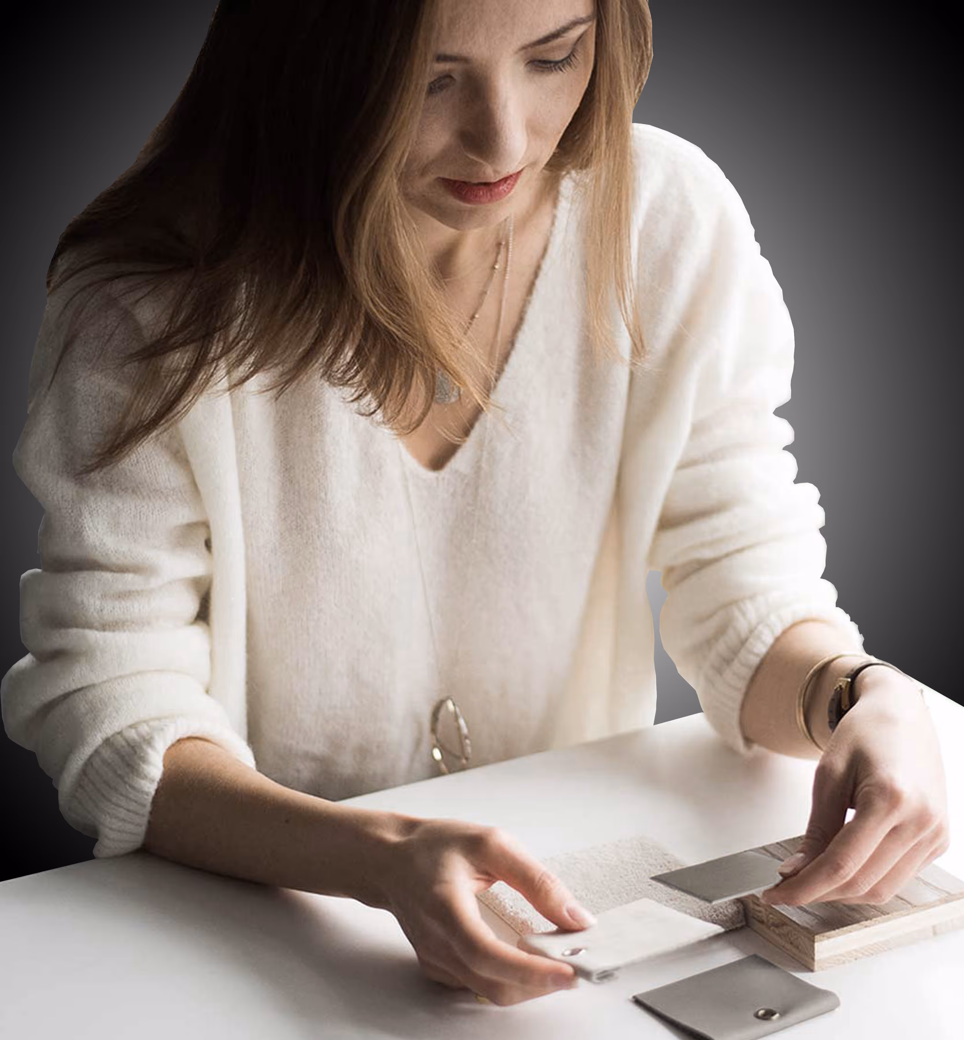 Woman in a white sweater examining different fabric and material swatches on a table.