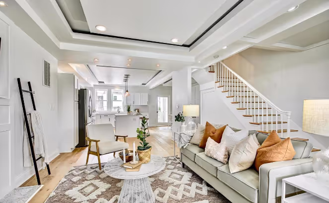 Renovated living room featuring an updated staircase with modern railings, new flooring, recessed lighting, and a stylish, open-concept design