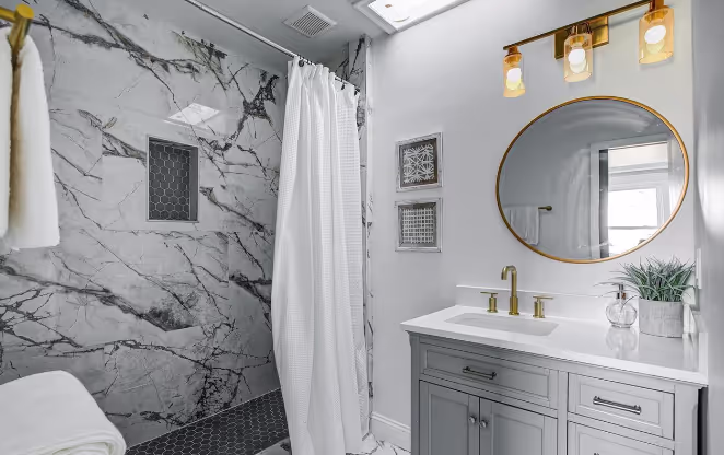 Modern renovated bathroom with grey mosaic tile shower floor, and updated vanity with clean, minimalist finishes