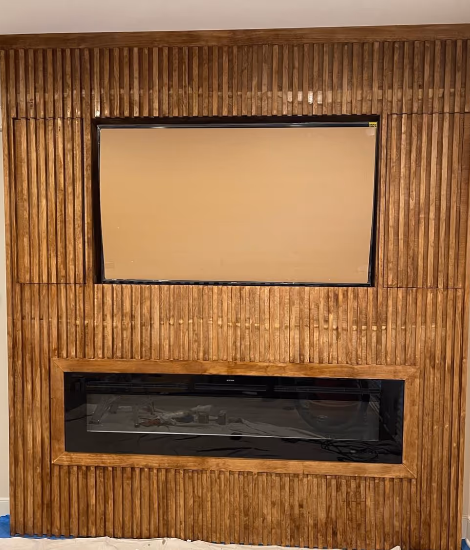Video of renovated living room showcasing an electric fireplace with wood-paneled surround and mounted TV, creating a warm and modern focal point